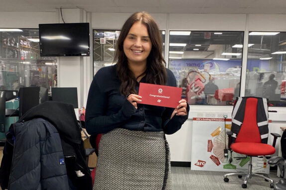 maia johnson dressed in black holding up her red employee of the month award.